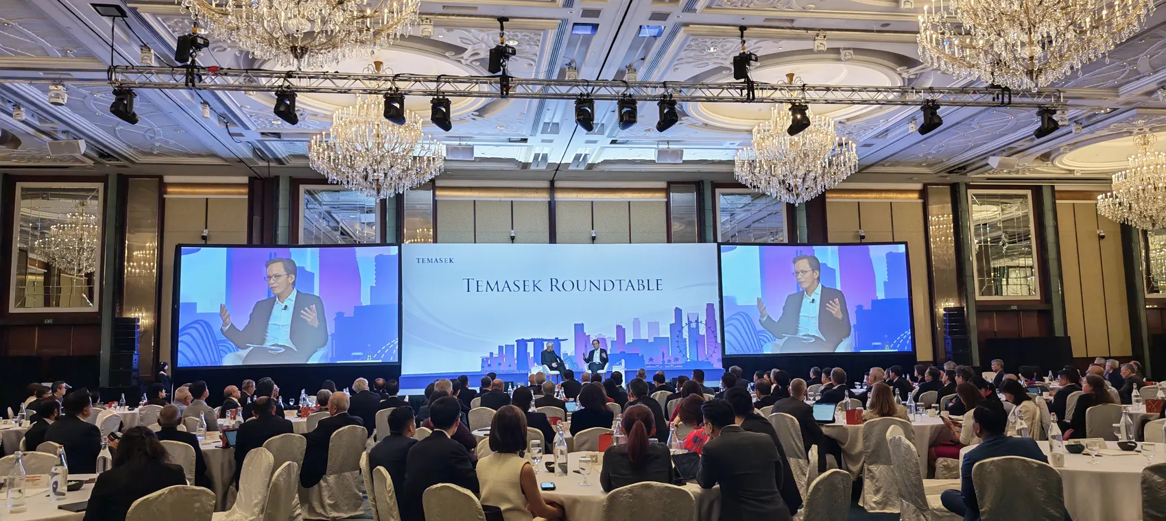Corporate conference ballroom with stage, screens and audience